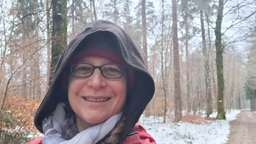 Susanne im Winterwald mit Kapuze, lachend