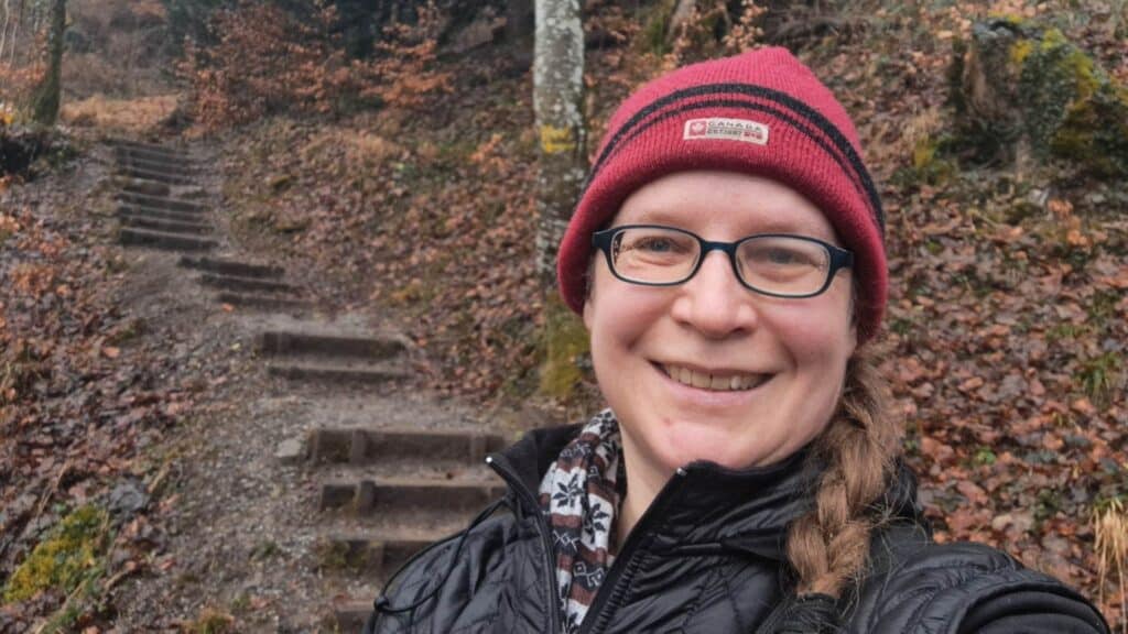 Selfie von Susanne im Wald mit roter Mütze.